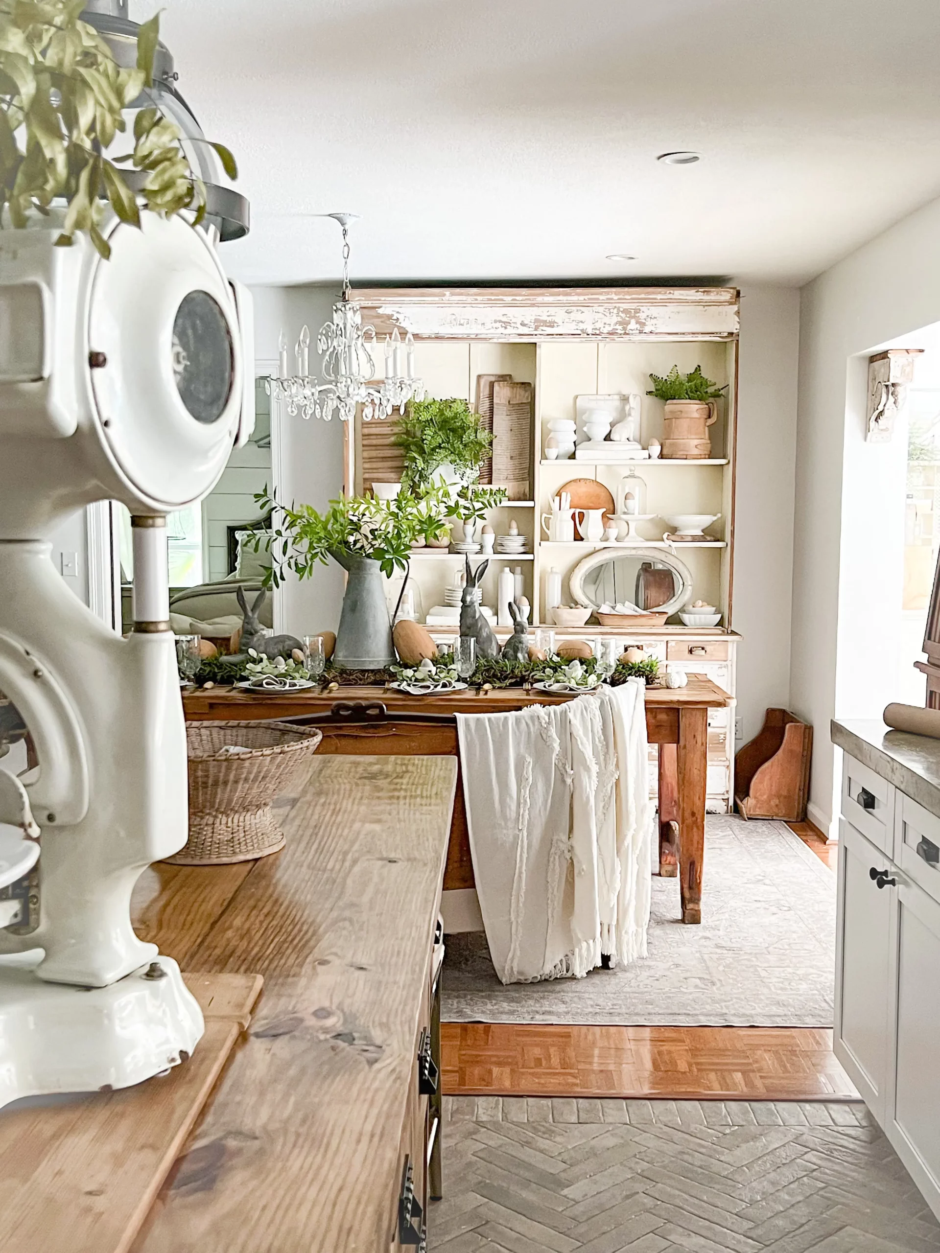 view of a fresh dining room with faux greenery and a beautiful white chippy apothecary