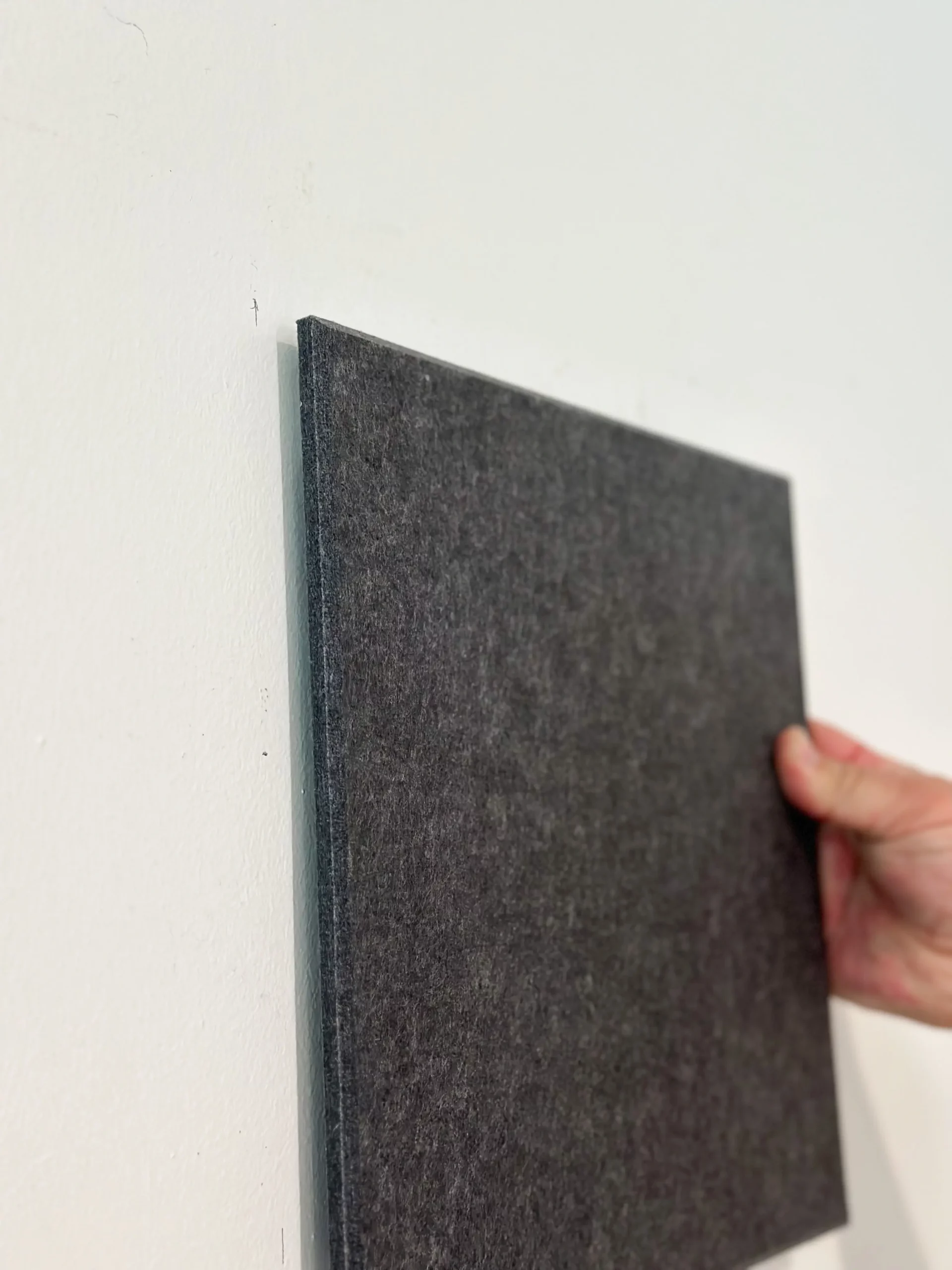 dark square of the felt tic-tac-toe board being placed on the wall