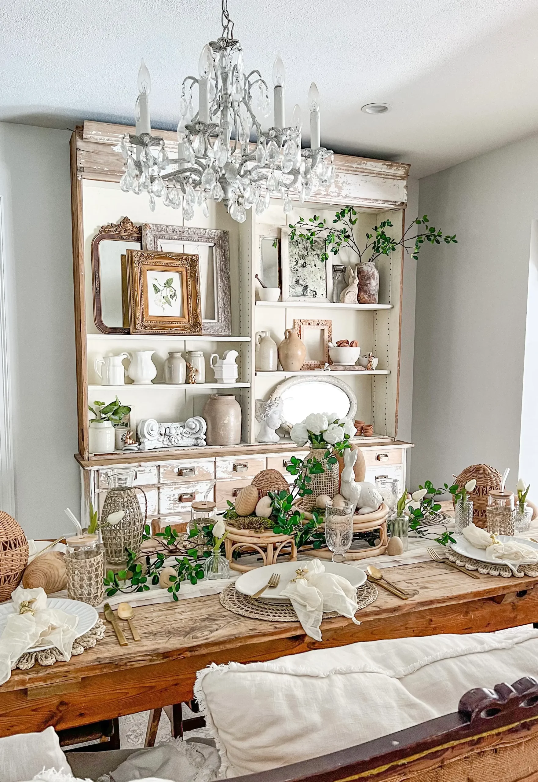 plants decorated throughout a dining room tablescape and a white apothecary with shelves styled for spring