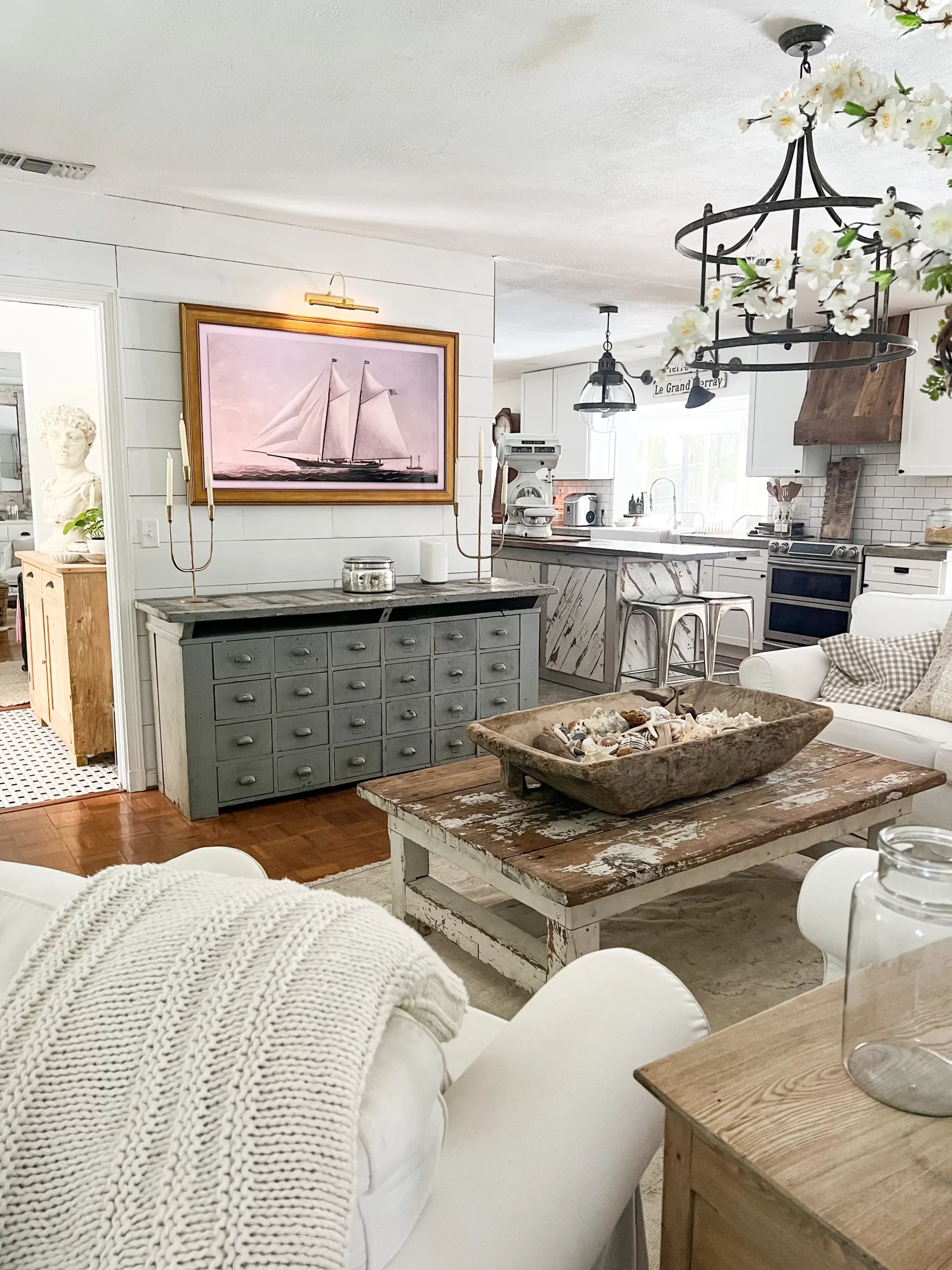 wide angle of a family room with a TV framed with a gold frame and a beautiful sailboat painting on the TV