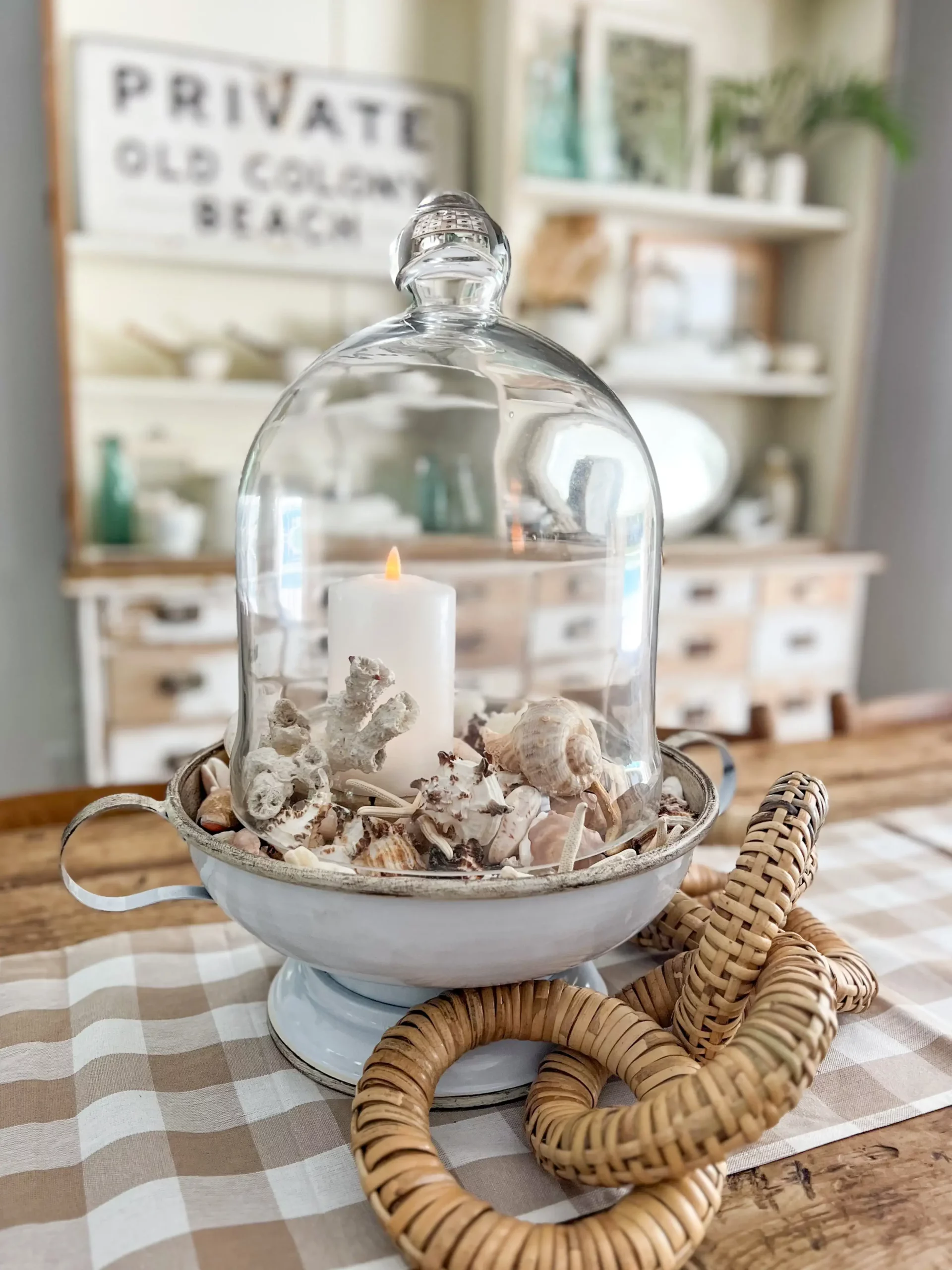 glass cloche over a bowl of small shells on a table
