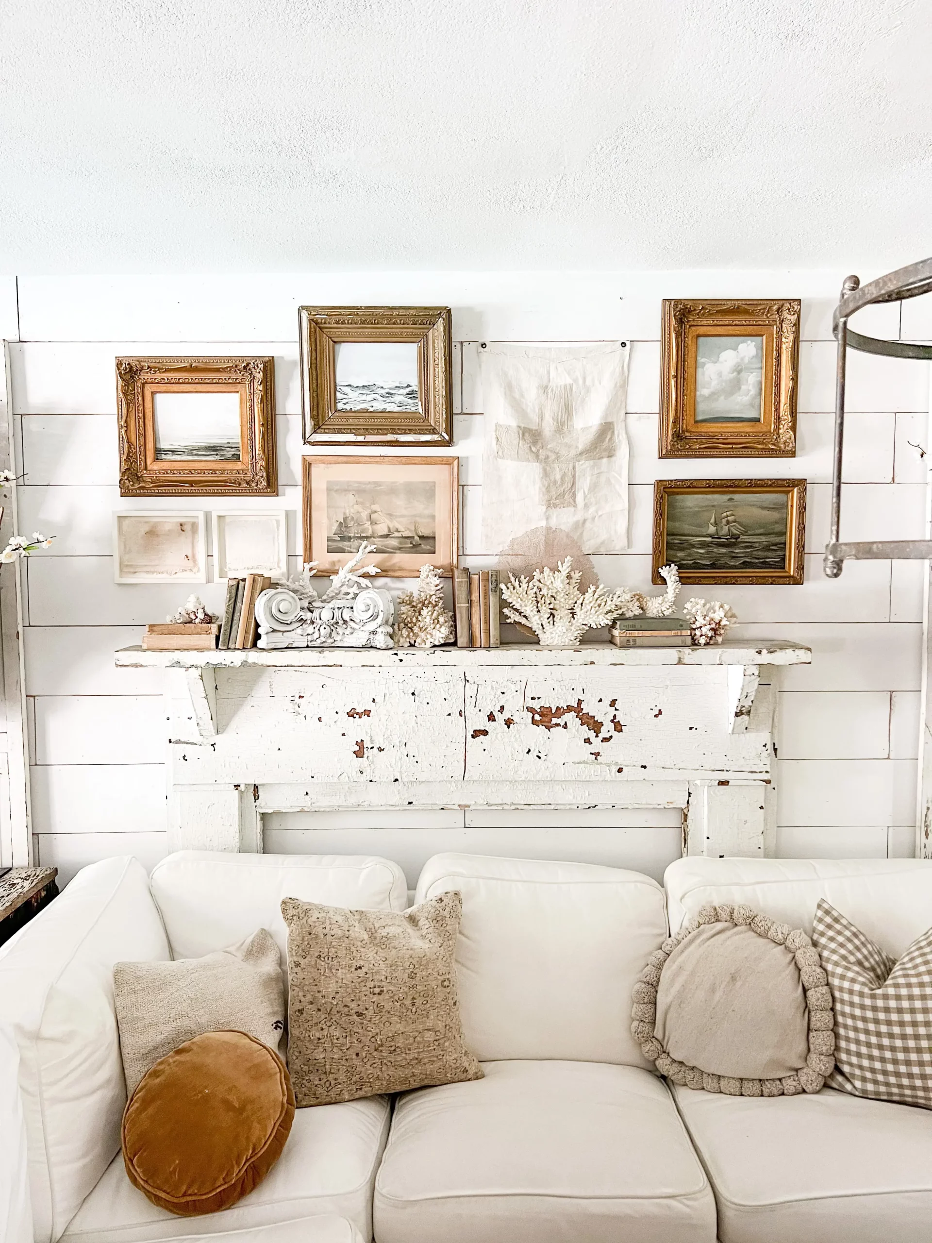 coral used on a gallery wall and styled on a white mantel in a coastal grandmother living room