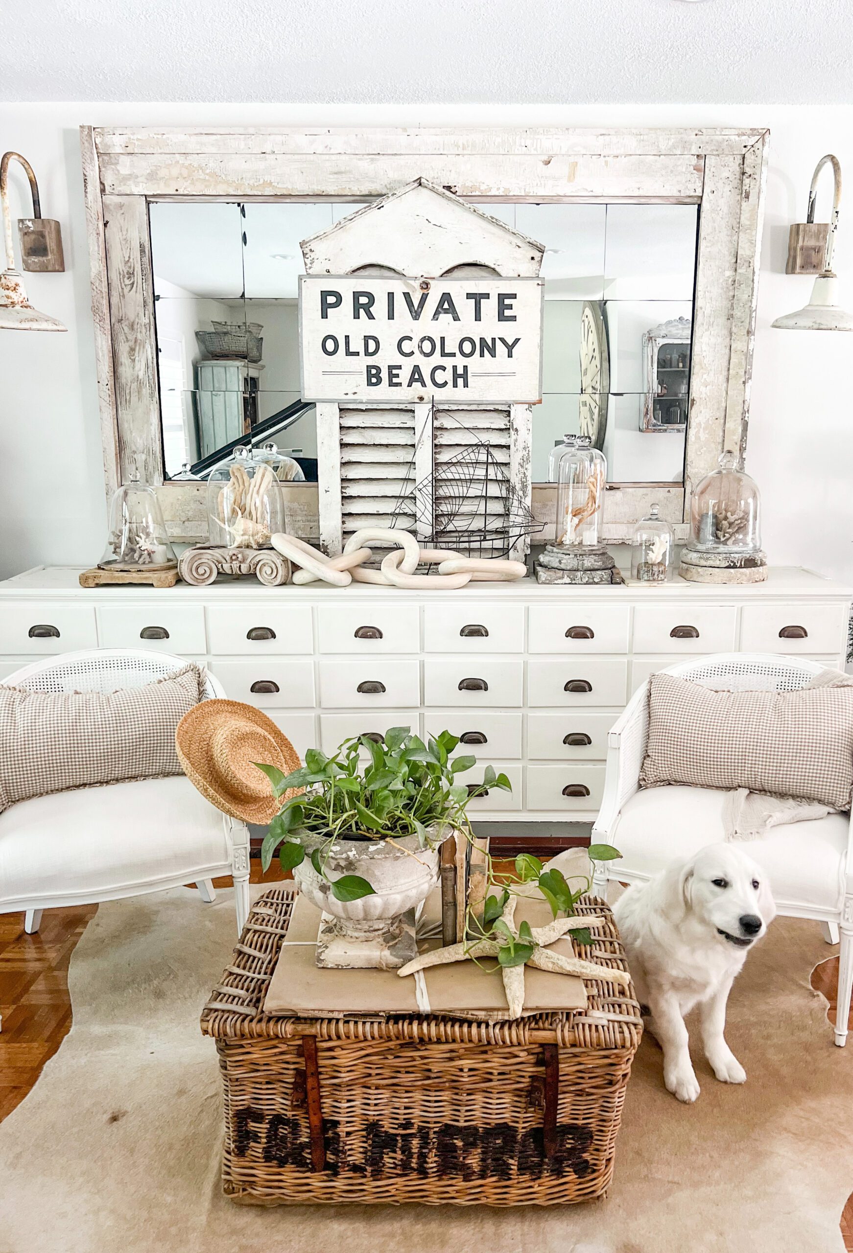 large white apothecary with a large mirror propped up on top and styled with various elements of coastal summer decor