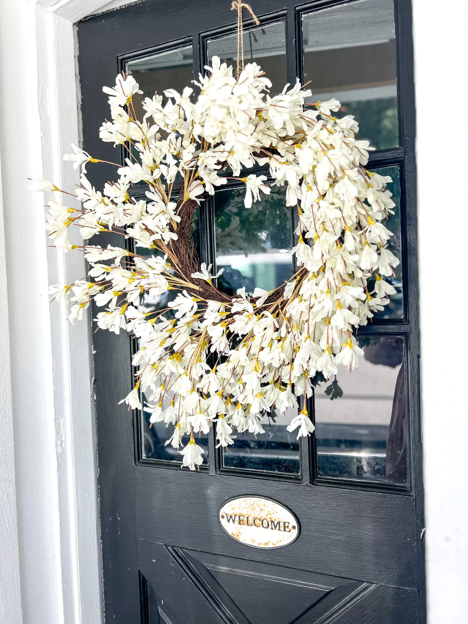 white forsythia wreath hung on the front door