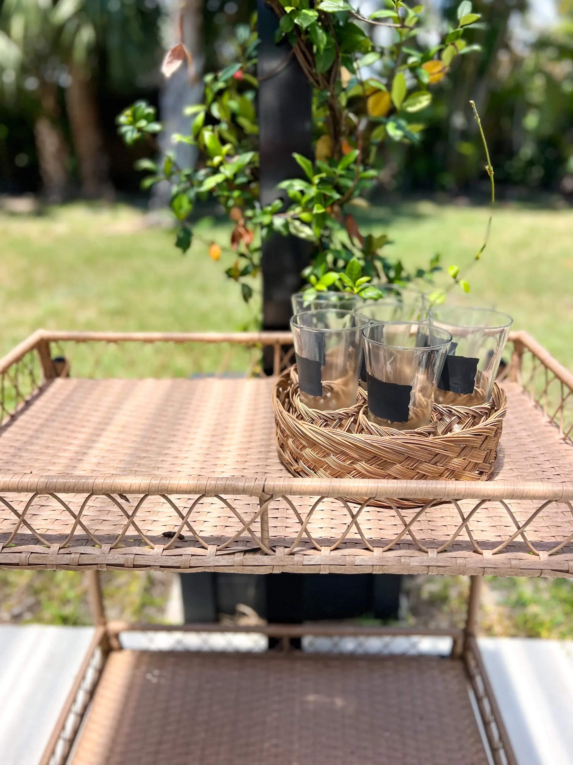 small rattan outdoor bar cart with a tray of water glasses