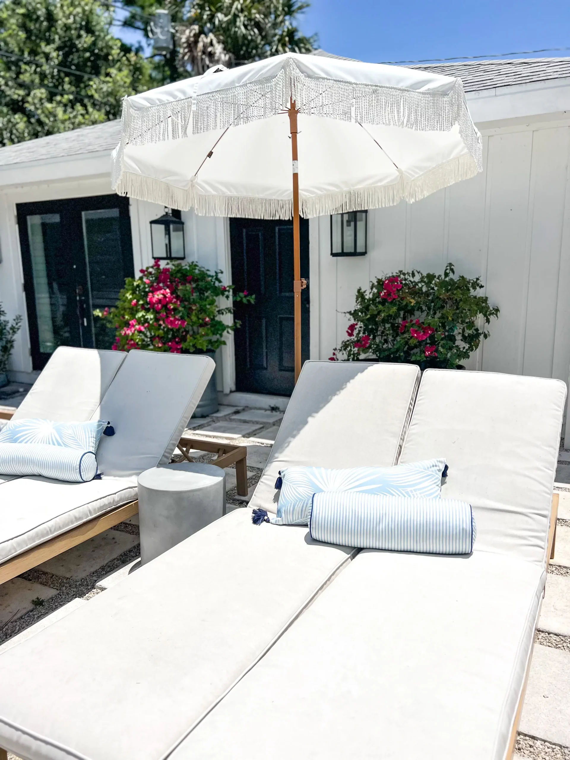 summer chaise loungers with a large white umbrella over them